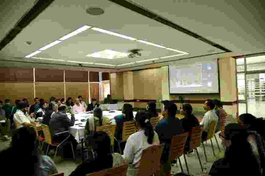 Hub colleagues and attendees taking part in the panel discussion during the Place of Groundwater event, seated in a horsehoe layout, with a screen showing those attendees and speakers taking part digitally